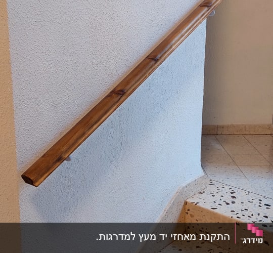 מסגרת עץ תלויה על קיר ליד מעקה עץ